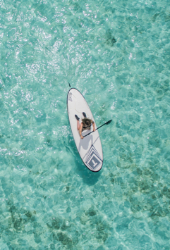 Active woman on a stand up paddleboard in clear blue water.